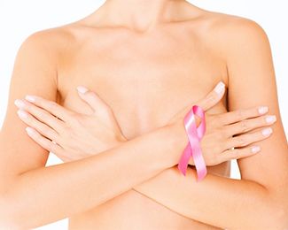 Woman holding arms crossed over naked chest with breast cancer awareness ribbon on wrist