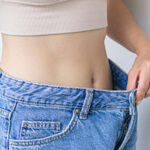 young woman tries on her jeans after a healthy weight loss
